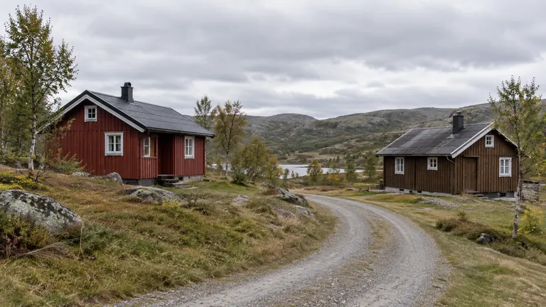 En rød og en brun hytte langs en grusvei i fjellet.